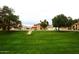 Neighborhood view of a beige two-story home with a red tile roof, front lawn, and mature trees at 4437 E Villa Theresa Dr, Phoenix, AZ 85032