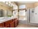 Bright bathroom featuring double sinks, soaking tub, glass shower, and decorative window at 5524 E Garnet Cir, Mesa, AZ 85206