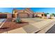 Front exterior of a home featuring desert landscaping, a three-car garage, and a well-maintained lawn at 5524 E Garnet Cir, Mesa, AZ 85206