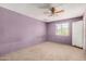 Simple bedroom featuring a ceiling fan, window with bars, carpeted floors, and lavender walls at 6426 W Mulberry Dr, Phoenix, AZ 85033