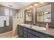 Bathroom featuring double sinks, granite counters, decorative mirrors, and a glass block window at 7101 E Cholla St, Scottsdale, AZ 85254