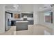 Bright kitchen featuring dark cabinetry, stainless appliances, an island with stone countertops and large window at 7551 W Pasadena Ave, Glendale, AZ 85303