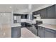 This bright kitchen features dark cabinetry, stainless appliances, and an island with stone countertops at 7551 W Pasadena Ave, Glendale, AZ 85303