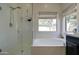 Bright bathroom featuring a glass-enclosed shower, and a soaking tub with a large window view at 10402 E Javelina Ave, Mesa, AZ 85209