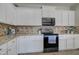 Well-equipped kitchen with white cabinets, a microwave and range, and granite countertops at 10402 E Javelina Ave, Mesa, AZ 85209