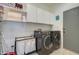 This laundry room features white walls, tile flooring, an LG washer and dryer and white cabinets at 10402 E Javelina Ave, Mesa, AZ 85209