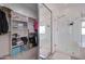 Spacious walk-in closet featuring custom shelving, hanging racks, and an adjacent frameless glass shower for spa-like experience at 10402 E Javelina Ave, Mesa, AZ 85209