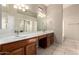 Well-lit bathroom features a dual sink vanity with a large mirror and tile flooring at 10923 W Ivory Ln, Avondale, AZ 85392