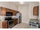 Kitchen with tile floors, wood cabinets, stainless steel refrigerator, granite counters, and double sink at 10923 W Ivory Ln, Avondale, AZ 85392