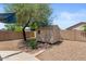 Backyard featuring a storage shed, gravel landscaping, and a mature tree at 13796 W Mauna Loa Ln, Surprise, AZ 85379