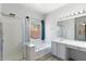 Bright bathroom featuring a walk-in shower, tub and a large mirror at 13796 W Mauna Loa Ln, Surprise, AZ 85379