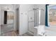 Bathroom with a glass enclosed shower, tub and a window bringing in natural light at 13796 W Mauna Loa Ln, Surprise, AZ 85379