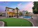 Spacious backyard with putting green, pool, covered patio, string lights and desert landscaping at 1574 E Scott Ave, Gilbert, AZ 85234