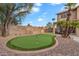 Attractive backyard putting green next to covered patio with seating, desert landscaping, and brick border at 1574 E Scott Ave, Gilbert, AZ 85234