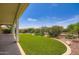 Lush backyard featuring manicured artificial grass, desert landscaping, and covered patio for outdoor enjoyment at 16729 W Alvarado Dr, Goodyear, AZ 85395