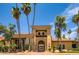 Elegant clubhouse entrance with desert landscaping, tall palm trees, and shaded entryway at 16729 W Alvarado Dr, Goodyear, AZ 85395