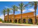 Clubhouse exterior showcasing arched windows, desert landscaping, and tall palm trees against a clear blue sky at 16729 W Alvarado Dr, Goodyear, AZ 85395