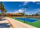 View of the community tennis courts with a clubhouse in the background on a sunny day at 16729 W Alvarado Dr, Goodyear, AZ 85395