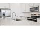 Detail shot of a kitchen featuring stainless steel appliances, white cabinets, tile backsplash, and a large sink at 18268 W La Senda Dr, Surprise, AZ 85387
