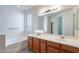 Bathroom features a double sink vanity with a large mirror, tub and a glass block window at 2024 W Darrel Rd, Phoenix, AZ 85041