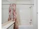 Bathroom features a shower over tub, white tiling, and neutral floral shower curtain at 2024 W Darrel Rd, Phoenix, AZ 85041