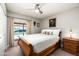 Cozy bedroom with wood sleigh bed, ceiling fan, and a view of the pool through the window at 2301 E Sunnyside Dr, Phoenix, AZ 85028