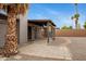 Backyard featuring desert landscaping, block fence, covered patio, and mature palm trees at 3106 S Extension Rd, Mesa, AZ 85210