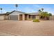 Charming brick home with a gray garage door, a desert landscape, and mature palm trees at 3106 S Extension Rd, Mesa, AZ 85210