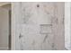 Modern shower featuring marble-patterned tile and a built-in niche for storage at 35314 N 31St Ave, Phoenix, AZ 85086