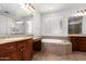 Bathroom with a large soaking tub, tiled surround, and wood vanities at 3818 E Quail Ave, Phoenix, AZ 85050