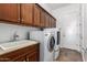 A laundry room featuring dark cabinets, a sink, and a washer and dryer unit at 3818 E Quail Ave, Phoenix, AZ 85050