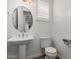 Elegant powder room featuring a pedestal sink, oval mirror, and white plantation shutters at 3818 E Quail Ave, Phoenix, AZ 85050