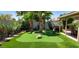 Backyard putting green with lush landscaping, palm trees, and a hot tub, creating a private oasis at 4617 E Emile Zola Ave, Phoenix, AZ 85032