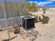 Close-up of an HVAC unit on a horse property, surrounded by lush trees and desert plants at 50525 W Whirly Bird Rd, Maricopa, AZ 85139