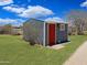 Exterior view of shed with painted red door on green landscape at 50525 W Whirly Bird Rd, Maricopa, AZ 85139