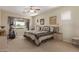 Cozy main bedroom showcasing natural light, a ceiling fan, an exercise machine, and serene outdoor views at 6418 S Pinaleno Pl, Chandler, AZ 85249