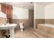 Bathroom with pedestal sink, toilet, shower, and a soaking tub with tile surround and steps at 7340 W Meadowbrook Ave, Phoenix, AZ 85033