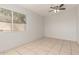 A bedroom with bright white walls and tile floors that features a ceiling fan and window at 7340 W Meadowbrook Ave, Phoenix, AZ 85033