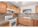 Cozy kitchen featuring wood cabinets, gas range, and tile backsplash with a bright window at 7340 W Meadowbrook Ave, Phoenix, AZ 85033