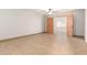 Spacious living room with light tile flooring and view to another room through wood paneled doors at 7340 W Meadowbrook Ave, Phoenix, AZ 85033