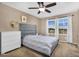 This bedroom includes a soft, grey bed, white dresser, and bright window views at 7718 W Pipestone Pl, Phoenix, AZ 85035
