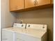 Convenient laundry area equipped with washer and dryer beneath storage cabinets at 8759 W Port Au Prince Ln, Peoria, AZ 85381