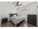 Simple bedroom with dark wood floors, fan, and a window letting in natural light at 10961 W Chase Ln, Avondale, AZ 85323
