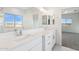 Bathroom features a double sink vanity, white cabinets, and views of the neighborhood through the window at 11227 E Crescent Ave, Mesa, AZ 85208