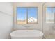 Bright main bathroom featuring a free-standing tub and a window with a view of the desert landscape at 11227 E Crescent Ave, Mesa, AZ 85208