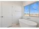Bright main bathroom featuring a free-standing tub and a window with a view of the desert landscape at 11227 E Crescent Ave, Mesa, AZ 85208