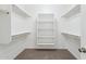 Well-lit walk-in closet boasts carpet flooring, white shelving, and rods for organized storage at 11227 E Crescent Ave, Mesa, AZ 85208