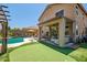 Back exterior shot of the home highlighting an outdoor covered seating area and a backyard pool and putting green at 11936 W Alvarado Rd, Avondale, AZ 85392