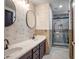 Elegant bathroom with double sinks, modern fixtures, stylish wallpaper, and a tiled shower with a glass door at 11936 W Alvarado Rd, Avondale, AZ 85392