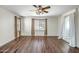 Bright bedroom featuring wood-look floors, neutral walls, multiple windows, and a ceiling fan with light fixture at 11936 W Alvarado Rd, Avondale, AZ 85392